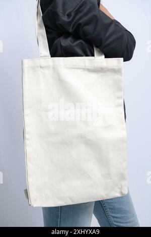 una donna che tiene in mano una borsa tote bianca vuota, utile per il design mockup Foto Stock