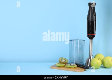 Kit frullatore a immersione, frutta fresca e coltello su sfondo azzurro, spazio per testo Foto Stock