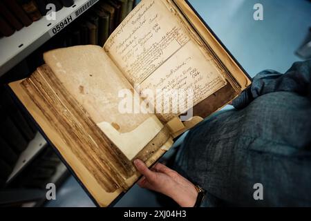 Un archivista tiene un libro in una stanza d'archivio presso il London Metropolitan Archives di Londra. Il secondo servizio di archiviazione più grande nel Regno Unito cambierà nome il mese prossimo, al fine di attirare nuovi visitatori e chiarire la natura delle sue vaste collezioni. London Metropolitan Archives, di proprietà e gestione della City of London Corporation, lascerà "Metropolitan" dal suo nome e dal 5 agosto diventerà noto come London Archives. Data foto: Martedì 16 luglio 2024. Foto Stock