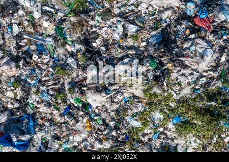 Vista dall'alto della grande discarica urbana piena di vari tipi di rifiuti e vegetazione sparsa, inquinamento ambientale. Foto Stock