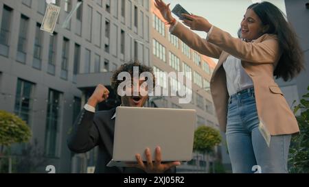 Due uomini d'affari in città indiano felice gioire urlare felice vincitore uomo d'affari uomo di lavoro festeggia online vincere laptop vincere lotteria finanziaria Foto Stock