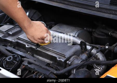 Cambio dell'olio. La mano di un uomo apre o chiude il tappo del bocchettone di rifornimento dell'olio. Cambio dell'olio in un motore diesel. Manutenzione della vettura. Vecchia macchina. L'inspec. Meccanico Foto Stock