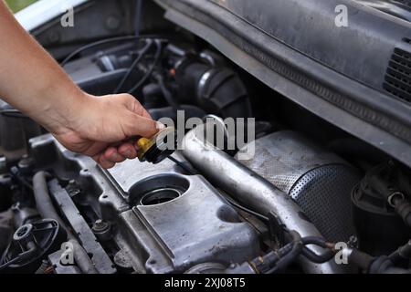 Cambio dell'olio. La mano di un uomo apre o chiude il tappo del bocchettone di rifornimento dell'olio. Cambio dell'olio in un motore diesel. Manutenzione della vettura. Vecchia macchina. L'inspec. Meccanico Foto Stock