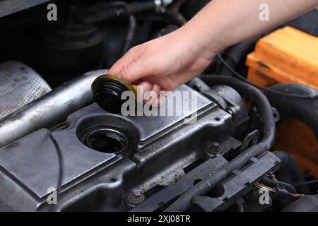 Cambio dell'olio. La mano di una donna apre o chiude il tappo del bocchettone di rifornimento dell'olio. Cambio dell'olio in un motore diesel. Manutenzione della vettura. Vecchia macchina Foto Stock