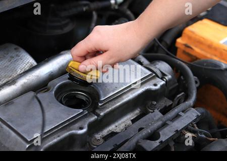 Cambio dell'olio. La mano di una donna apre o chiude il tappo del bocchettone di rifornimento dell'olio. Cambio dell'olio in un motore diesel. Manutenzione della vettura. Vecchia macchina Foto Stock