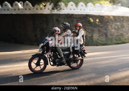 Una famiglia in moto a Kandy, Sri Lanka. Un adulto guida mentre due bambini e un altro adulto viaggiano come passeggeri Foto Stock