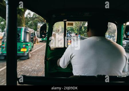 Vista del sedile del passeggero di un conducente di tuktuk che guida lungo una trafficata strada principale dello Sri Lanka. Foto Stock