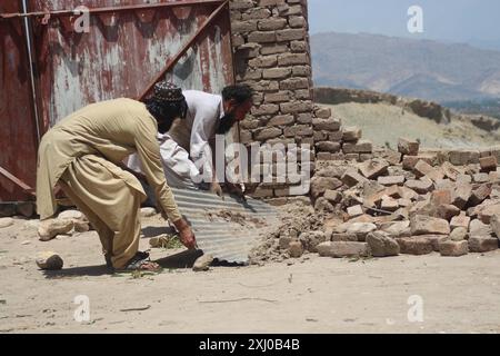 Nangarhar, Afghanistan. 15 luglio 2024. I residenti ripuliscono le rovine in un'area colpita dalle inondazioni nel distretto di Surkh Rod, provincia di Nangarhar, Afghanistan orientale, 15 luglio 2024. Il bilancio delle vittime per le precipitazioni e le inondazioni nella provincia di Nangarhar, nell'Afghanistan orientale, è salito a 40 e il numero dei feriti ha raggiunto i 347, il Ministero della salute pubblica del paese ha riferito martedì. Crediti: Aimal Zahir/Xinhua/Alamy Live News Foto Stock