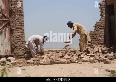 Nangarhar, Afghanistan. 15 luglio 2024. I residenti ripuliscono le rovine in un'area colpita dalle inondazioni nel distretto di Surkh Rod, provincia di Nangarhar, Afghanistan orientale, 15 luglio 2024. Il bilancio delle vittime per le precipitazioni e le inondazioni nella provincia di Nangarhar, nell'Afghanistan orientale, è salito a 40 e il numero dei feriti ha raggiunto i 347, il Ministero della salute pubblica del paese ha riferito martedì. Crediti: Aimal Zahir/Xinhua/Alamy Live News Foto Stock