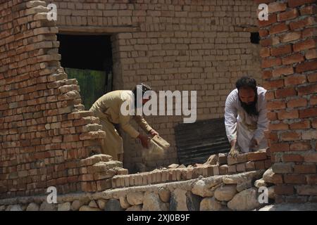 Nangarhar, Afghanistan. 15 luglio 2024. I residenti ripuliscono le rovine in un'area colpita dalle inondazioni nel distretto di Surkh Rod, provincia di Nangarhar, Afghanistan orientale, 15 luglio 2024. Il bilancio delle vittime per le precipitazioni e le inondazioni nella provincia di Nangarhar, nell'Afghanistan orientale, è salito a 40 e il numero dei feriti ha raggiunto i 347, il Ministero della salute pubblica del paese ha riferito martedì. Crediti: Aimal Zahir/Xinhua/Alamy Live News Foto Stock