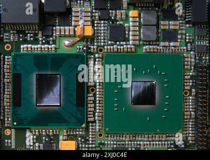 Primo piano dettagliato di una scheda a circuito stampato elettronica che mostra microchip, resistori e altri componenti, che rappresentano la tecnologia e l'hardware moderni. Foto Stock