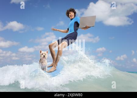 Giovane uomo in muta con un cane che cavalca una tavola da surf in mare e utilizza un computer portatile Foto Stock