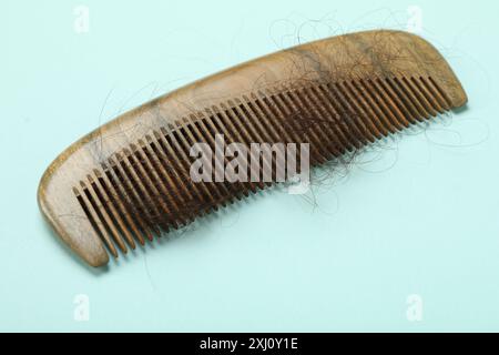 Un pettine con capelli persi su sfondo azzurro. Problema di alopecia Foto Stock