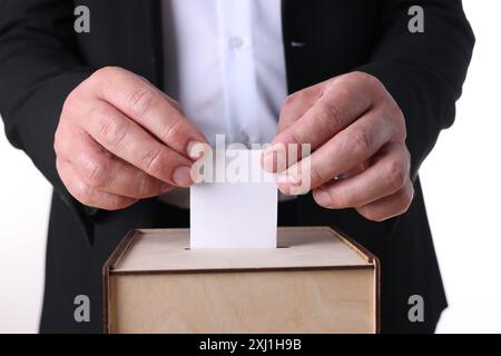 Uomo che mette il suo voto nelle urne su sfondo bianco, primo piano Foto Stock