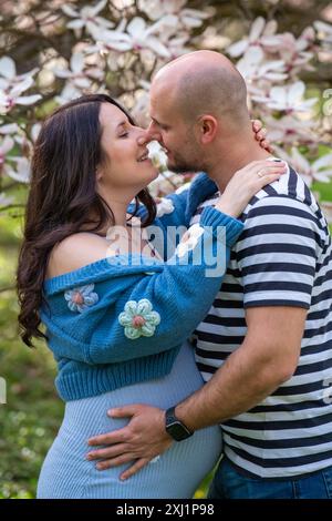 Una famiglia felice aspetta un bambino ed esprime il loro amore l'uno per l'altro con un bacio tenero. Gravidanza, amore nelle relazioni Foto Stock