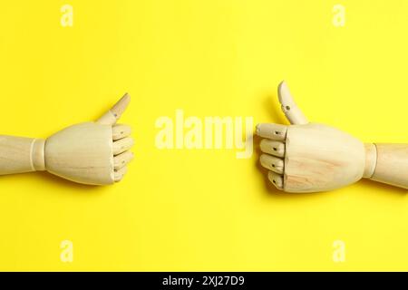 Manichini in legno su fondo giallo, giacitura piatta Foto Stock