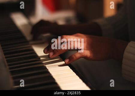 Un'immagine accattivante delle mani di un uomo nero che suona un vecchio pianoforte honky tonk, catturato con un'ampia apertura. Questa scena incarna creatività e ispirazione Foto Stock