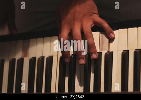 Un'immagine accattivante delle mani di un uomo nero che suona un vecchio pianoforte honky tonk, catturato con un'ampia apertura. Questa scena incarna creatività e ispirazione Foto Stock