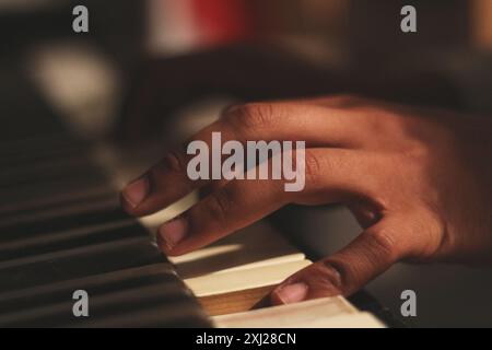 Un'immagine accattivante delle mani di un uomo nero che suona un vecchio pianoforte honky tonk, catturato con un'ampia apertura. Questa scena incarna creatività e ispirazione Foto Stock