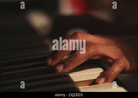 Un'immagine accattivante delle mani di un uomo nero che suona un vecchio pianoforte honky tonk, catturato con un'ampia apertura. Questa scena incarna creatività e ispirazione Foto Stock