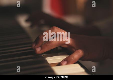 Un'immagine accattivante delle mani di un uomo nero che suona un vecchio pianoforte honky tonk, catturato con un'ampia apertura. Questa scena incarna creatività e ispirazione Foto Stock