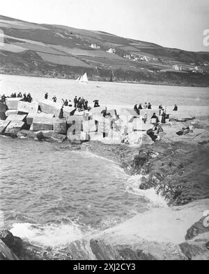 La frangiflutti che fu distrutta da una tempesta notturna nel 1884, con persone sulle rocce, Port Erin Bay, Isola di Man. Questa fotografia proviene da un originale edoardiano, intorno al 1910. L'originale faceva parte di un album di 150 fotografie di albume, di qualità variabile, molte delle quali ho fotografato. La collezione includeva immagini provenienti in particolare dall'Isola di Man e dalla contea inglese, Devonshire. Le annotazioni sono state incluse nell'album ma, sfortunatamente, non c'erano date specifiche. Le foto originali erano in media 6 x 4 ½ pollici. Foto Stock