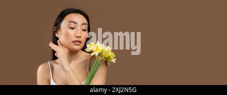Giovane bella signora giapponese che posa con fiori di narcisi gialli Foto Stock