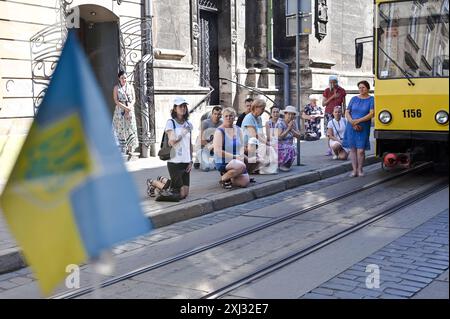 LEOPOLI, UCRAINA - 13 LUGLIO 2024 - persone inginocchiate per rendere omaggio al sotnyk dell'Esercito insurrezionale ucraino (UPA) Evhen Shtendera, morto in Canada il 23 agosto 2022, per essere sepolto a Leopoli, Ucraina occidentale. Foto Stock