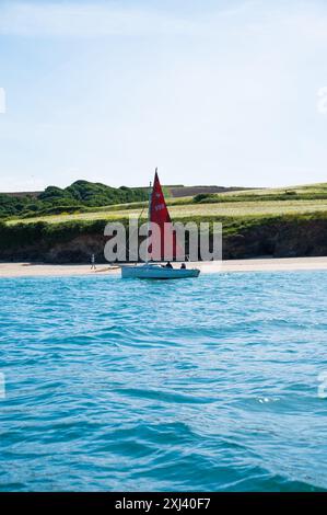 Uomo e donna che navigano su una piccola barca sotto vela a poppa sull'estuario del cammello vicino a Padstow, nella Cornovaglia settentrionale, Inghilterra, Regno Unito Foto Stock