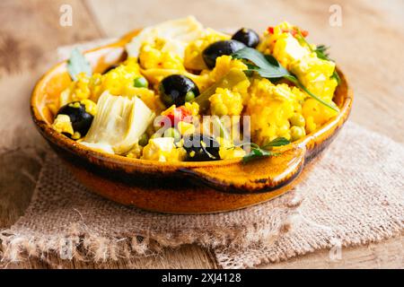 Paella vegetariana con carciofo, olive nere, fagioli verdi e peperone rosso. Foto Stock