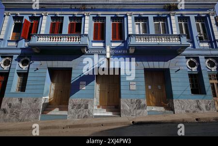 501 Correos Central Post Office facciata sud, edificio a due piani in stile eclettico con cartelli sul muro che mostrano gli orari di apertura. Santiago-Cuba. Foto Stock