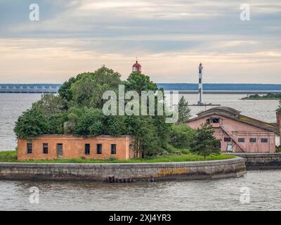 Piccola isola con un edificio rosso e due fari, circondata dall'acqua sotto un cielo nuvoloso, kronstadt, sankt petersburg, russia Foto Stock