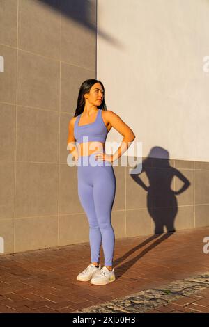 Una bruna caucasica vestita con abbigliamento sportivo all'illuminazione del tramonto Foto Stock