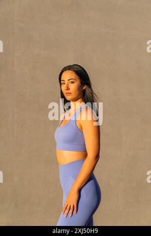 Una ragazza bruna caucasica vestita con abbigliamento sportivo all'illuminazione del tramonto Foto Stock