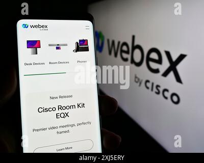 Stoccarda, Germania, 02-19-2024: Persona che detiene un telefono cellulare con pagina web della società statunitense di comunicazioni unificate Webex by Cisco davanti al logo. Concentrati Foto Stock