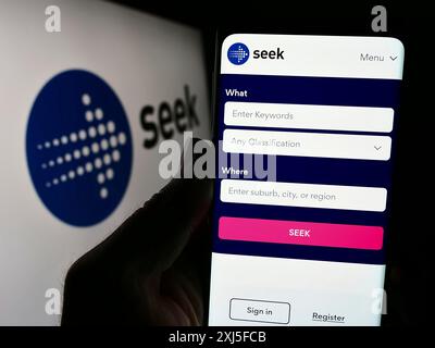 Stoccarda, Germania, 02-22-2024: Persona che detiene un cellulare con pagina web della società australiana di piattaforma di lavoro SEEK Limited davanti al logo. Concentrati Foto Stock