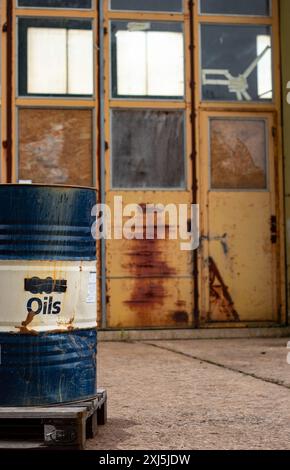 Rusty vecchio tamburo di petrolio in un deposito di rifiuti abbandonato. Stile retrò industriale Foto Stock