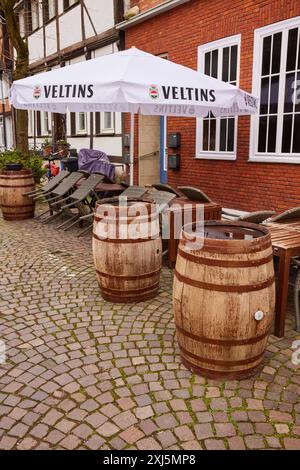 Vecchie botti di vino o birra come decorazione e un ombrellone con pubblicità Veltins nell'area esterna di un ristorante a Warendorf, Warendorf Foto Stock