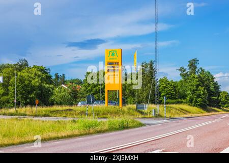 Stazione di servizio con cartello giallo Preem che mostra i prezzi del carburante, situata a lato della strada con vegetazione e alberi sullo sfondo. Svezia. Europa. Foto Stock