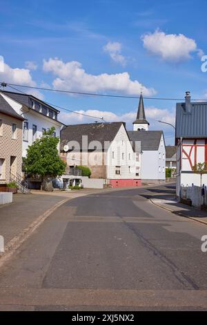 Strada con case sotto un cielo blu con nuvole di cumulus a Beuren, Eifel, distretto di Cochem-Zell, Renania-Palatinato, Germania Foto Stock