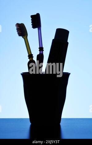 Spazzolini da denti e dentifricio in un bicchiere Foto Stock