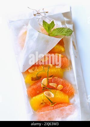 Agrumi, mandorle e menta tagliate a fette sottili cotte in carta cera Foto Stock