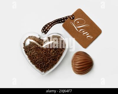 Cuore di plastica riempito di vermicelli di cioccolato e tagga con la parola amore Foto Stock