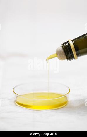 Versare l'olio d'oliva in un piccolo piatto rotondo Foto Stock