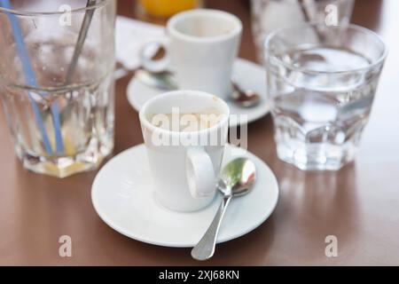 Bicchiere vuoto di succo d'arancia, tazza vuota di espresso e il conto su un tavolo in un bistrot Foto Stock