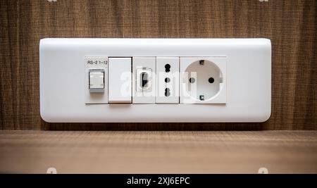 Vista ravvicinata di un moderno pannello bianco con prese elettriche standard europee, porta USB, connettore Internet RJ-45 e interruttori luce ag Foto Stock