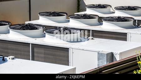 Diverse unità di condizionamento dell'aria industriali installate sul tetto di un edificio commerciale, che mostrano le infrastrutture urbane e la moderna tecnologia HVAC. Bianco Foto Stock