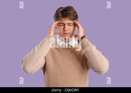 Giovane uomo che soffre di mal di testa su sfondo lilla Foto Stock