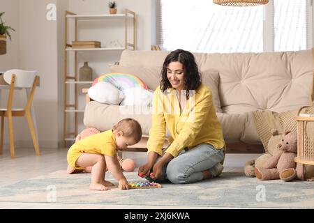 Bella, giovane, felice madre e piccolo bambino che gioca con lo xilofono a casa Foto Stock