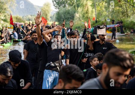 I musulmani sciiti del Kashmir gridano slogan filo-palestinesi durante una processione il nono giorno di Muharram. Il 9 di Muharram, le tranquille acque di Srinagar assistono a una processione di muharram unica e toccante, mentre i devoti a bordo delle barche rendono omaggio, mescolando tradizione e tranquillità bellezza del Lago dal. Muharram è il primo mese del calendario islamico, e uno dei mesi più sacri dell'Islam. I musulmani sciiti commemorano Muharram come un mese di lutto in ricordo del martirio di Imam Hussain, nipote del profeta Maometto. L'imam Hussain fu martirizzato ad Ashura, il decimo giorno di Muharram, durin Foto Stock